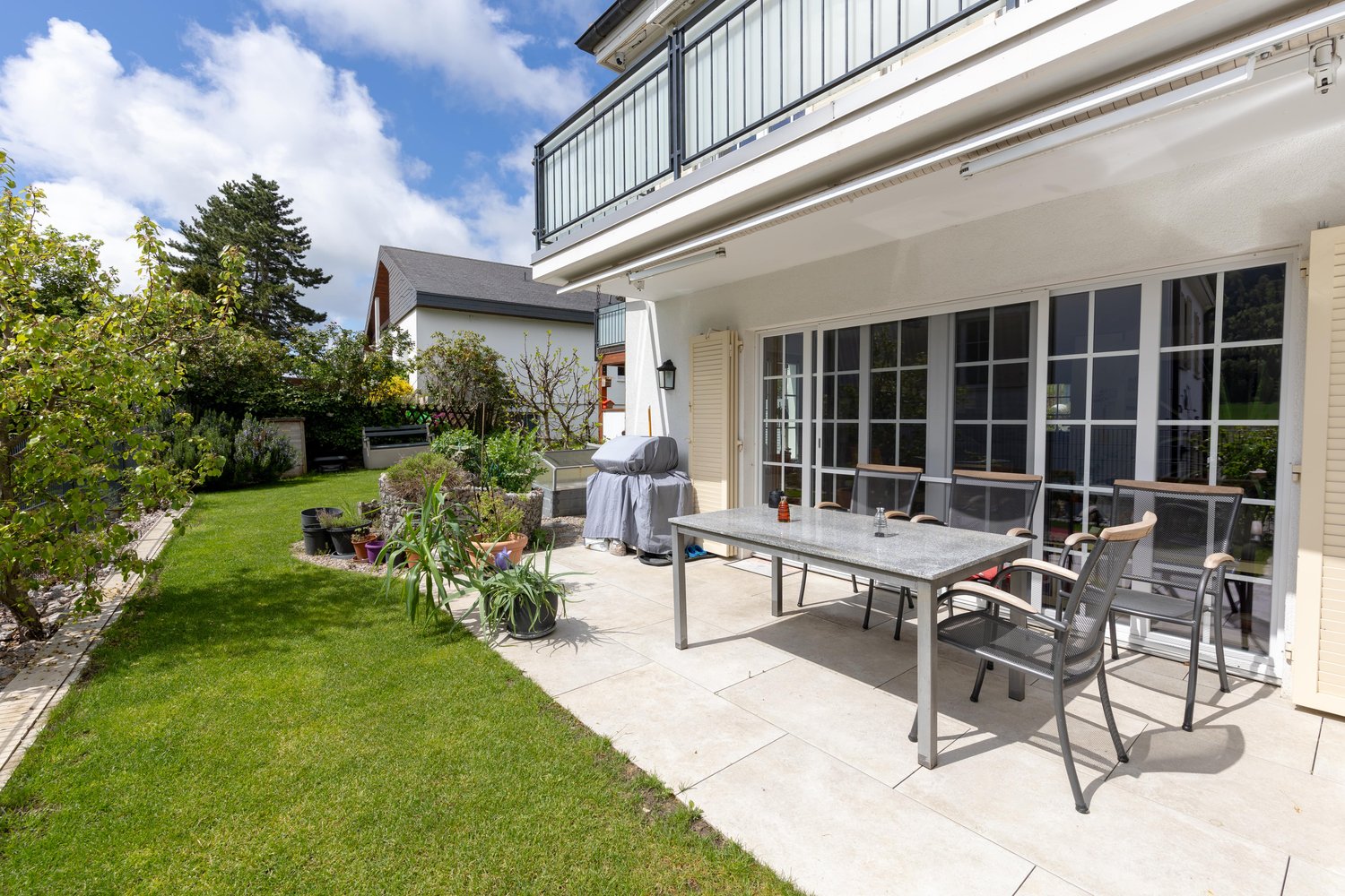 patio with table and chairs, plants, grass, balcony