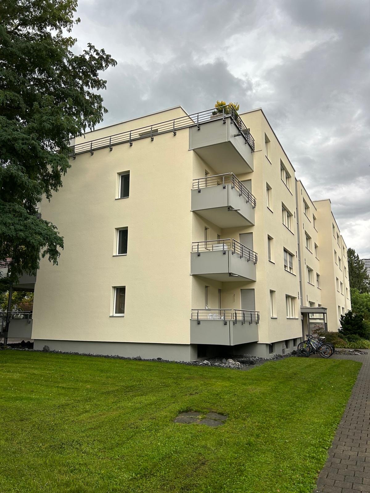 4 story building, yellow paint, balconies, green lawn in front
