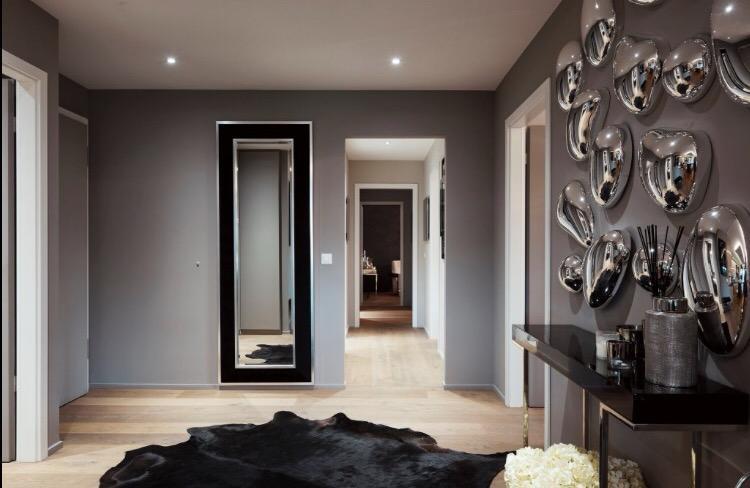 Modern room with gray walls, large mirror, wooden floor, black furry rug, console table with decorative items