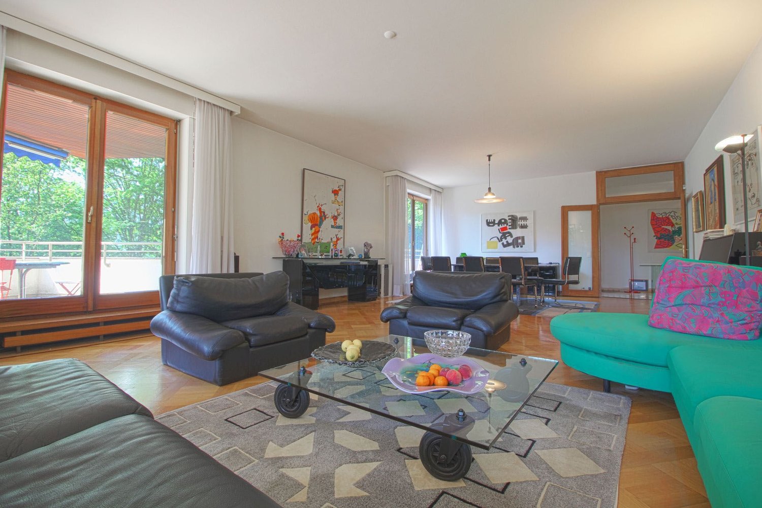 Leather sofas, wooden floor, large windows, balcony, sliding doors, table with fruit