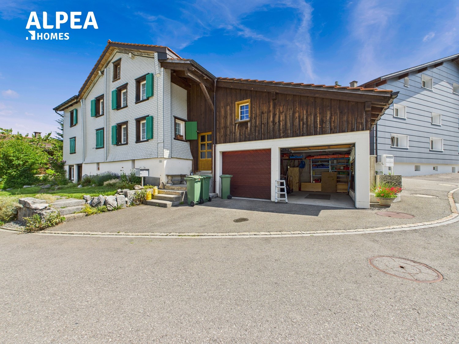 Detached house with brick lower part, green shutters, driveway with garage