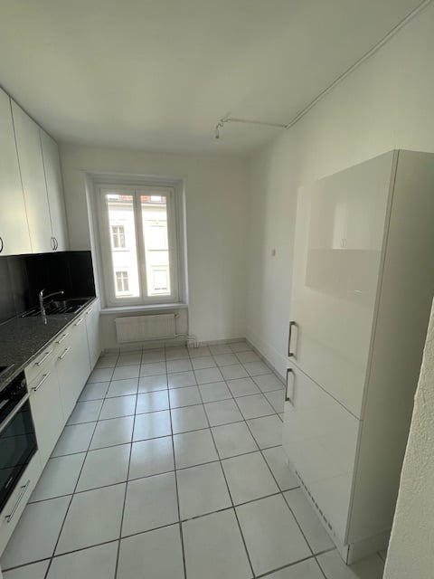 Modern kitchen, white cabinets, tiled floor, sink, refrigerator, large window