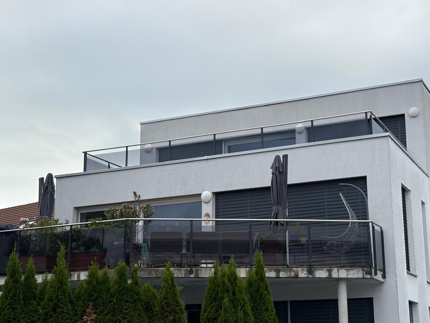 modern 2-story house, white exterior, gray roof, glass balconies, greenery