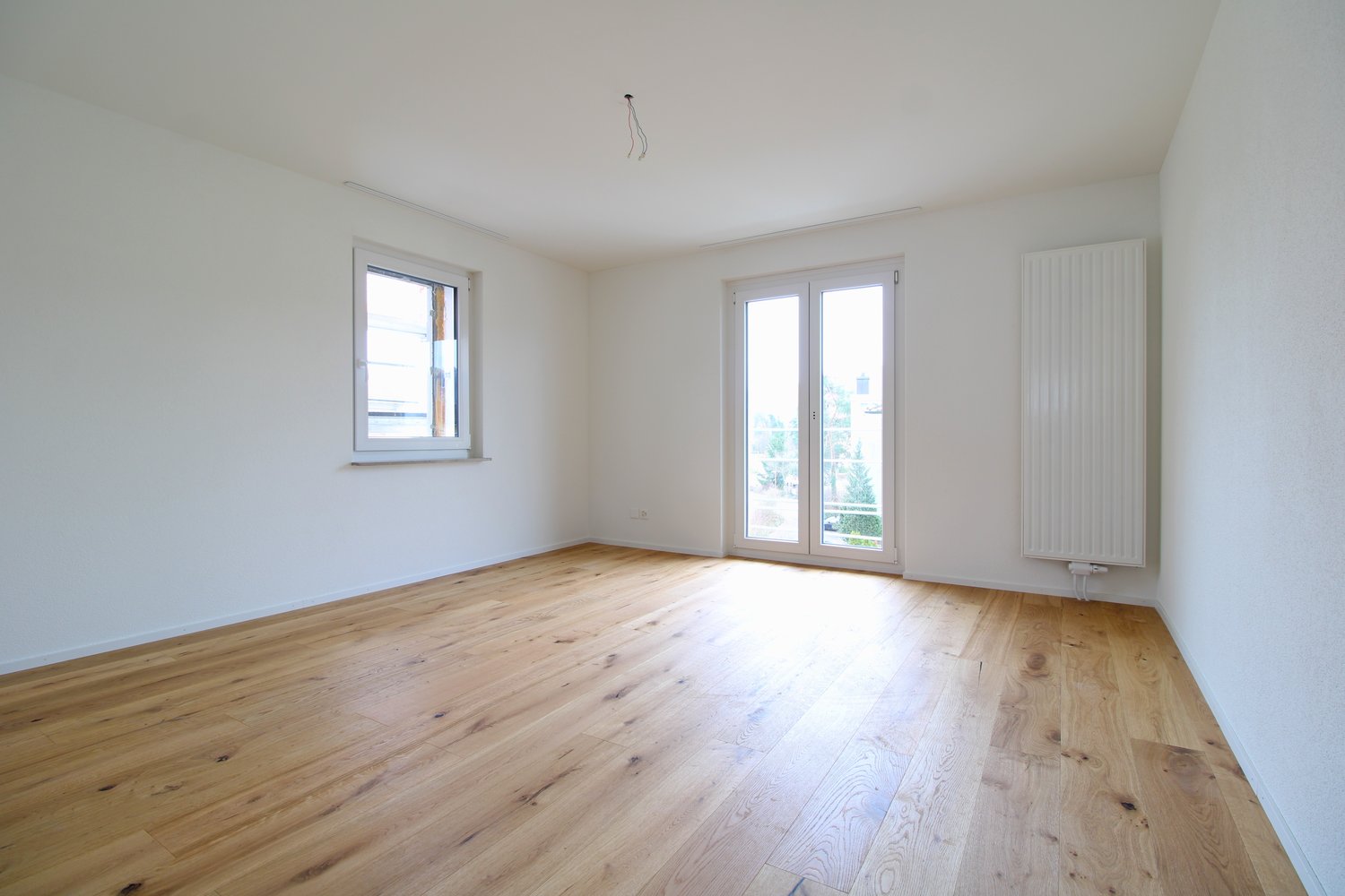 white walls, wooden floor, sliding glass doors, window, and radiator