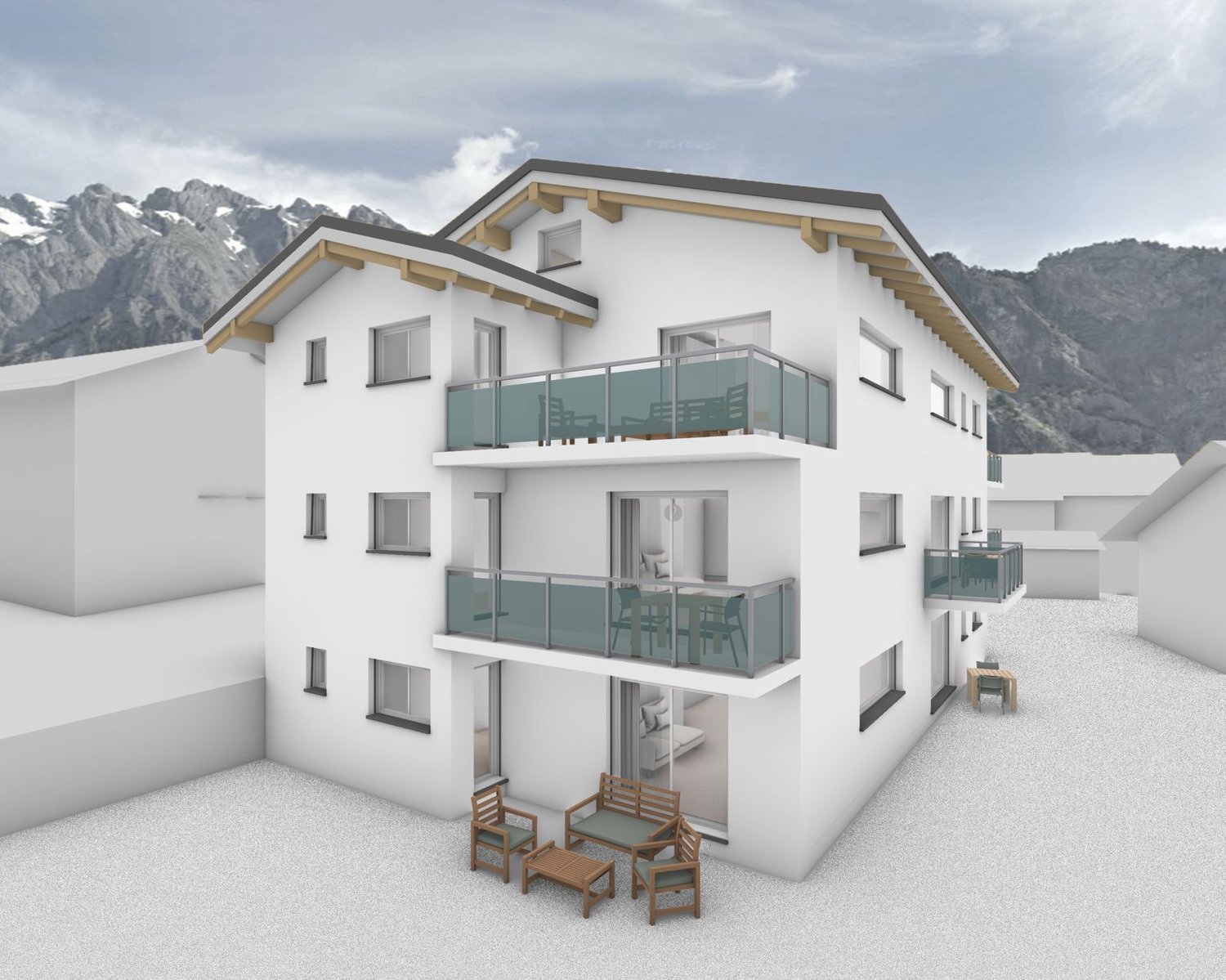 3-story apartment building with white exterior, wooden beams, and large balconies with glass railings. The building is situated in a mountainous landscape with snow-capped peaks in the background.