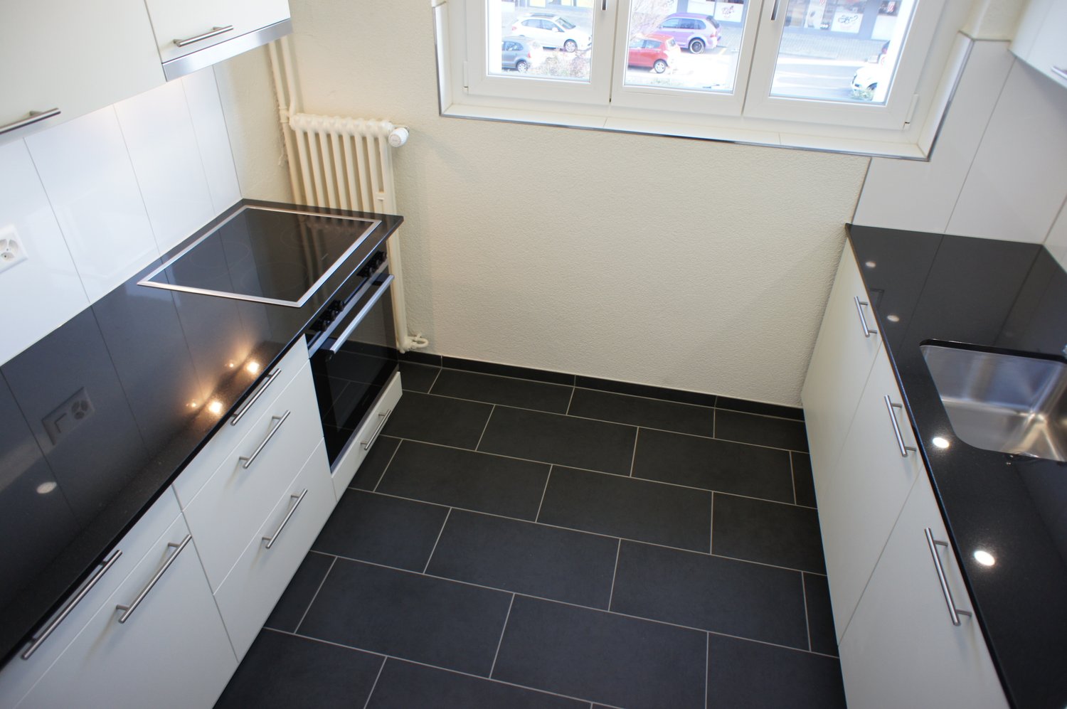 kitchen with black tiles, induction cooker, electric oven, dishwasher, stainless steel sink, white cabinets