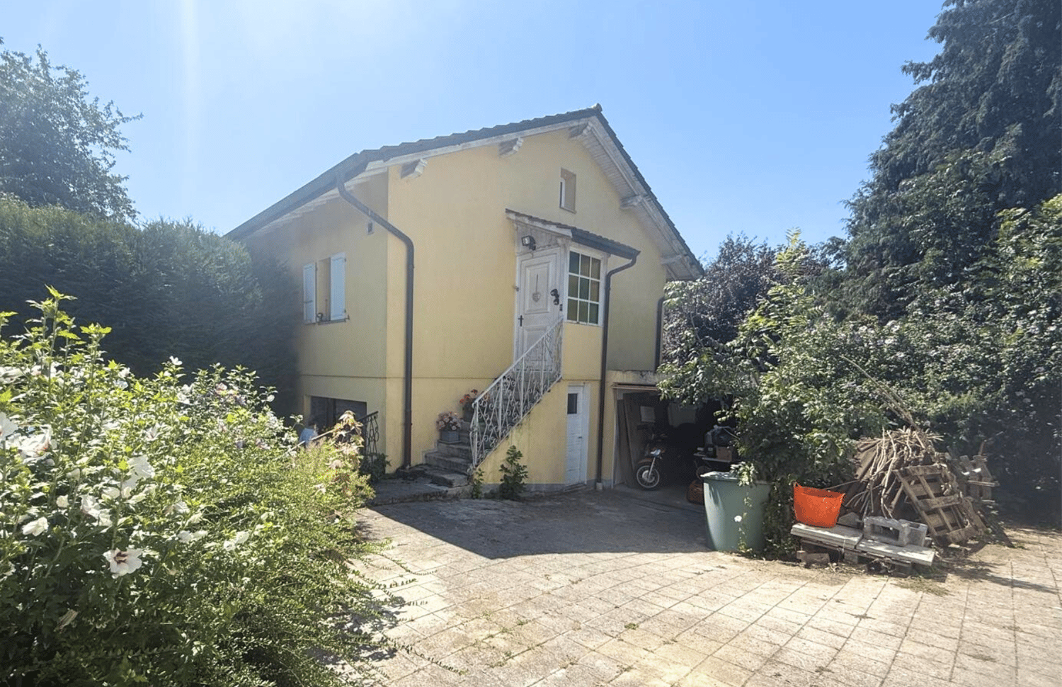 Single story house, yellow painted exterior, garage attached, brick flooring in driveway
