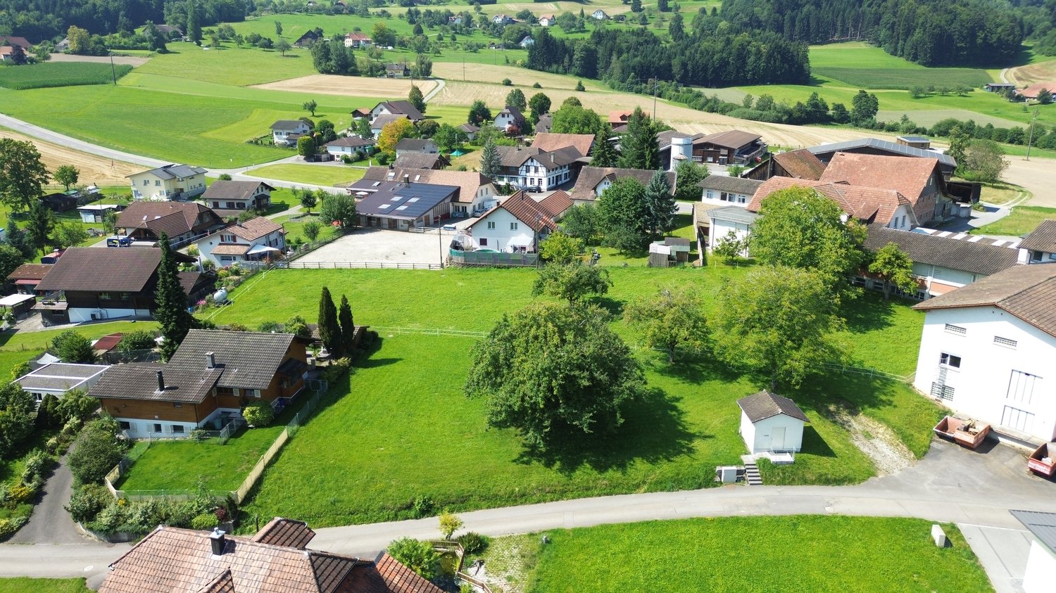 Cluster of small houses with brown roofs, green lawns, rural setting, and solar panels on one house