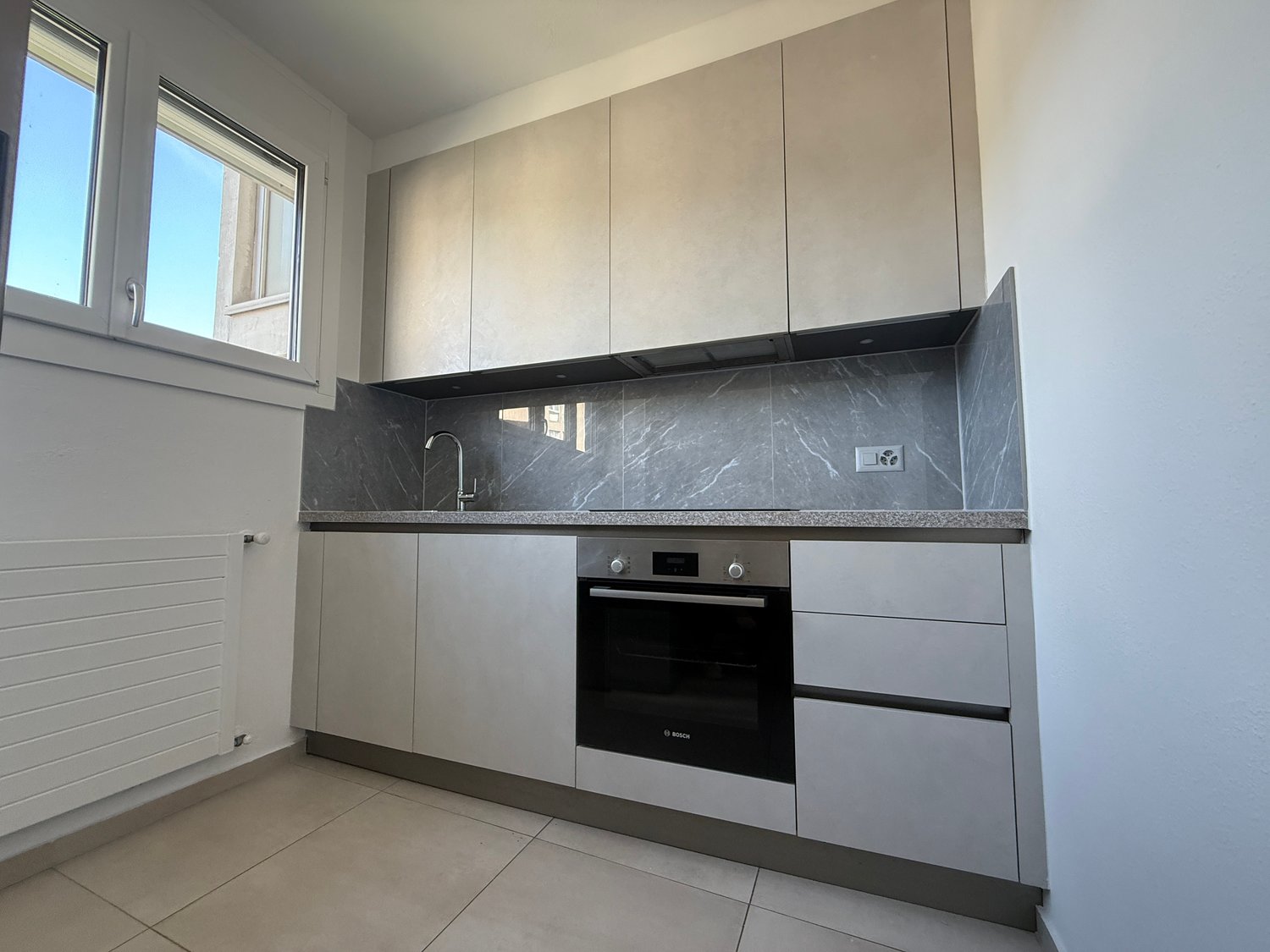 Modern minimalist design, tile floor, white cabinets, Bosch oven, stainless steel sink