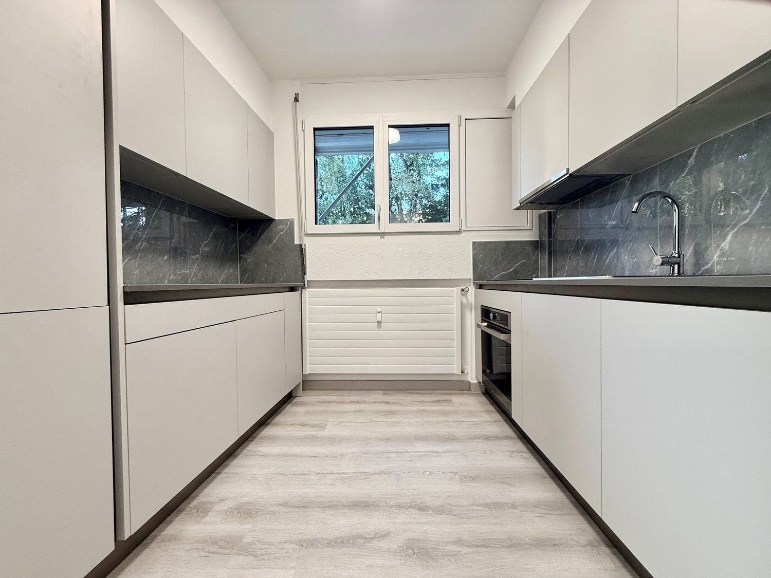 modern kitchen, white cabinets, wooden flooring, granite countertops, integrated appliances, bright windows, kitchen island