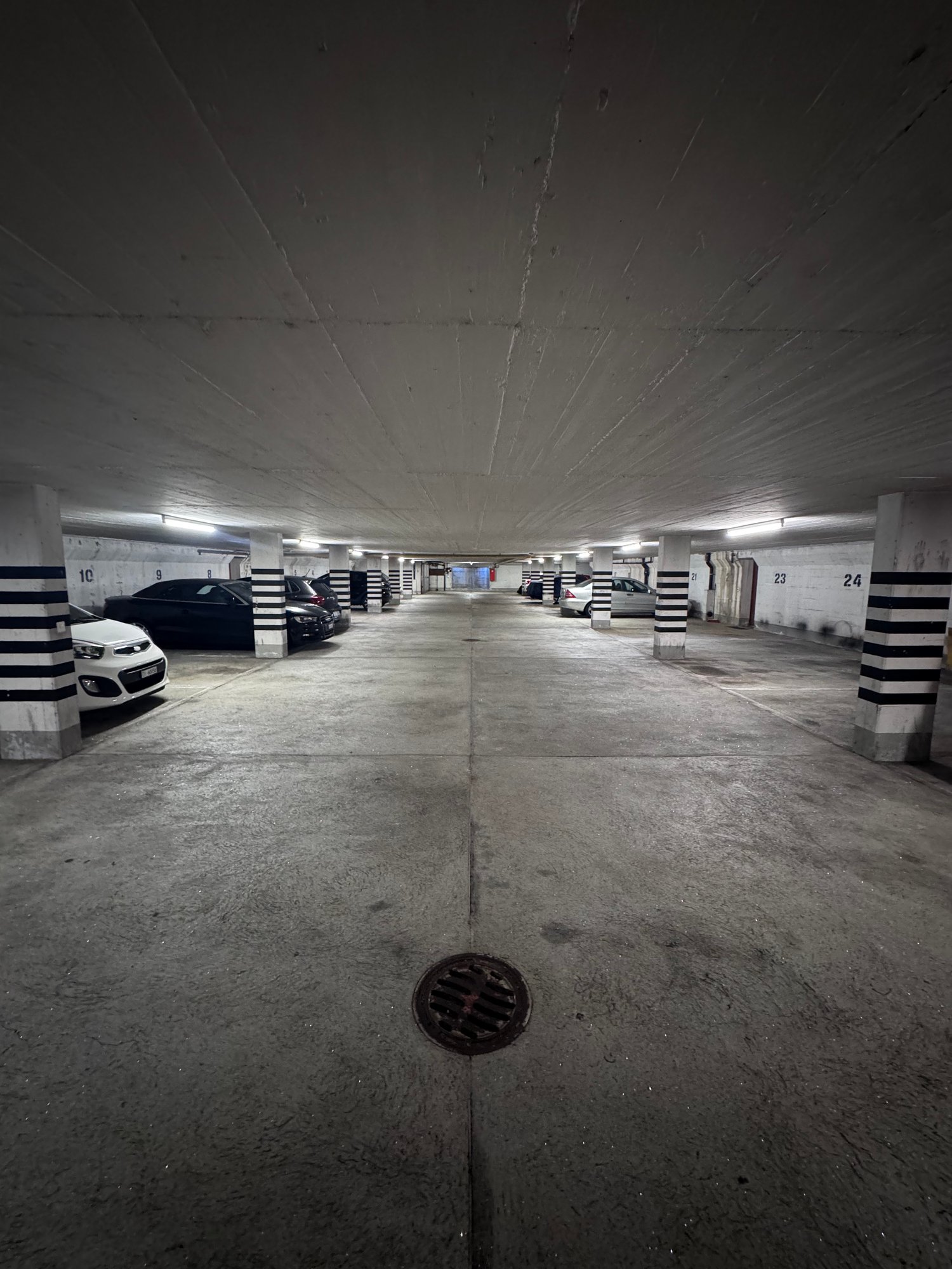 underground parking lot, white and black painted pillars, multiple parking spaces