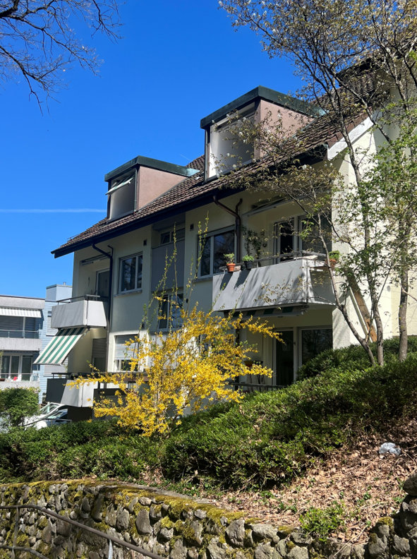 3 story house, white exterior, brown roof, multiple balconies, green awnings, surrounded by greenery