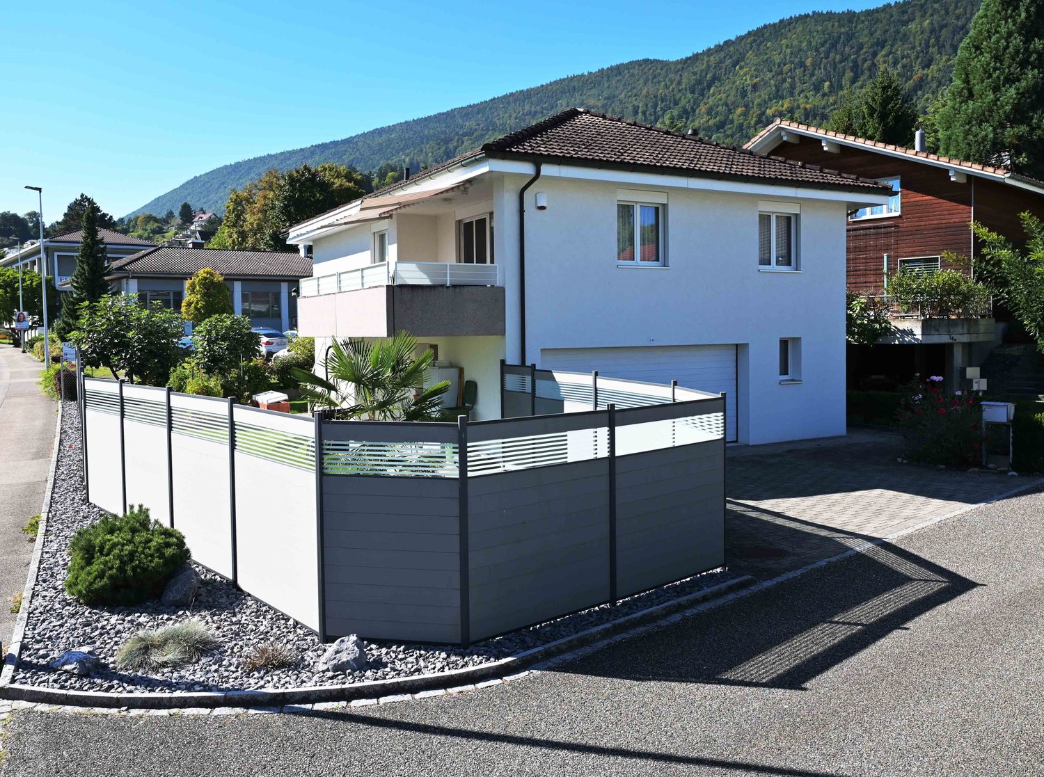 2 story house, white walls, brown roof, garage, balcony, garden, paved driveway