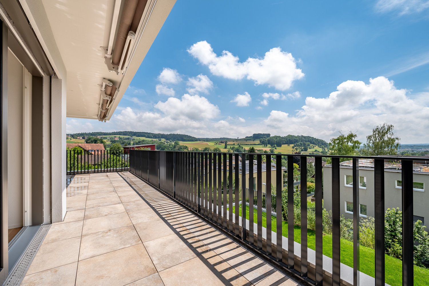 modern balcony with black railings and tile flooring, open view of the countryside