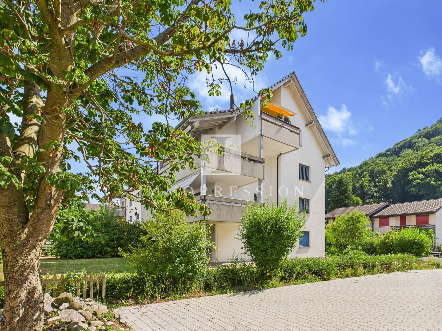 2-storey building, white paint, balcony on the second floor, tree in front