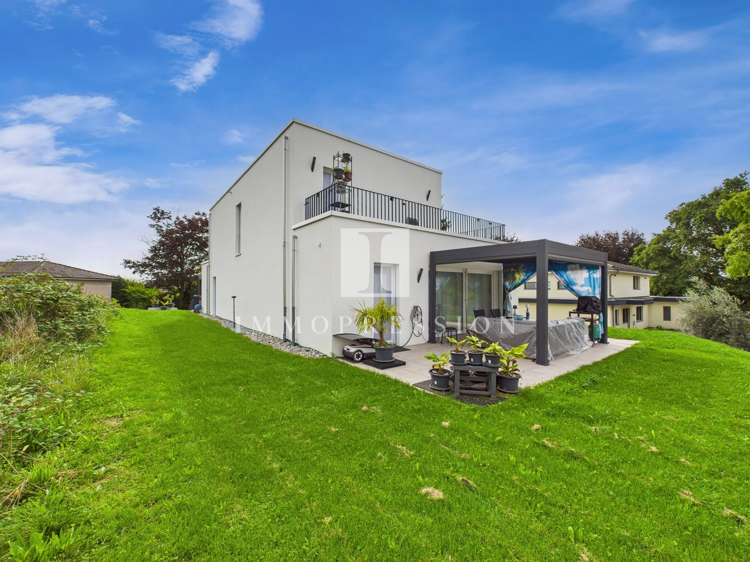 Modern 2 story house, white exterior, well-maintained lawn, large balcony, outdoor seating area