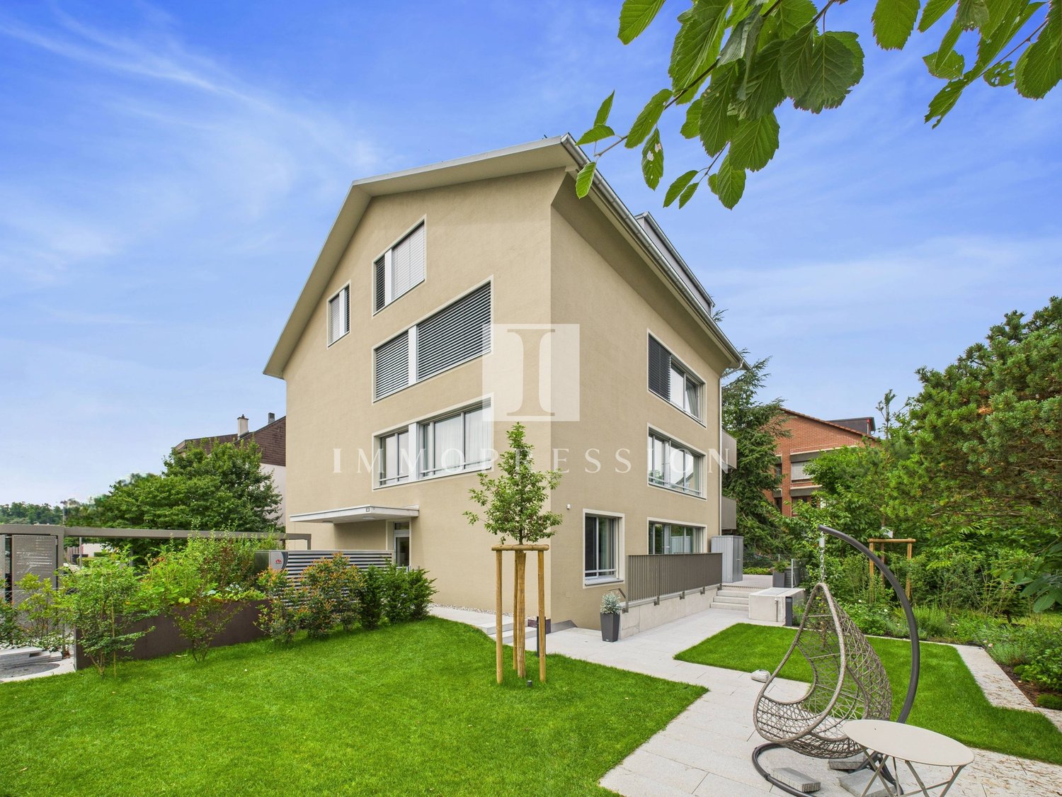 2 story house, beige exterior, large windows, well-maintained garden, patio, trees, plants, swing, table