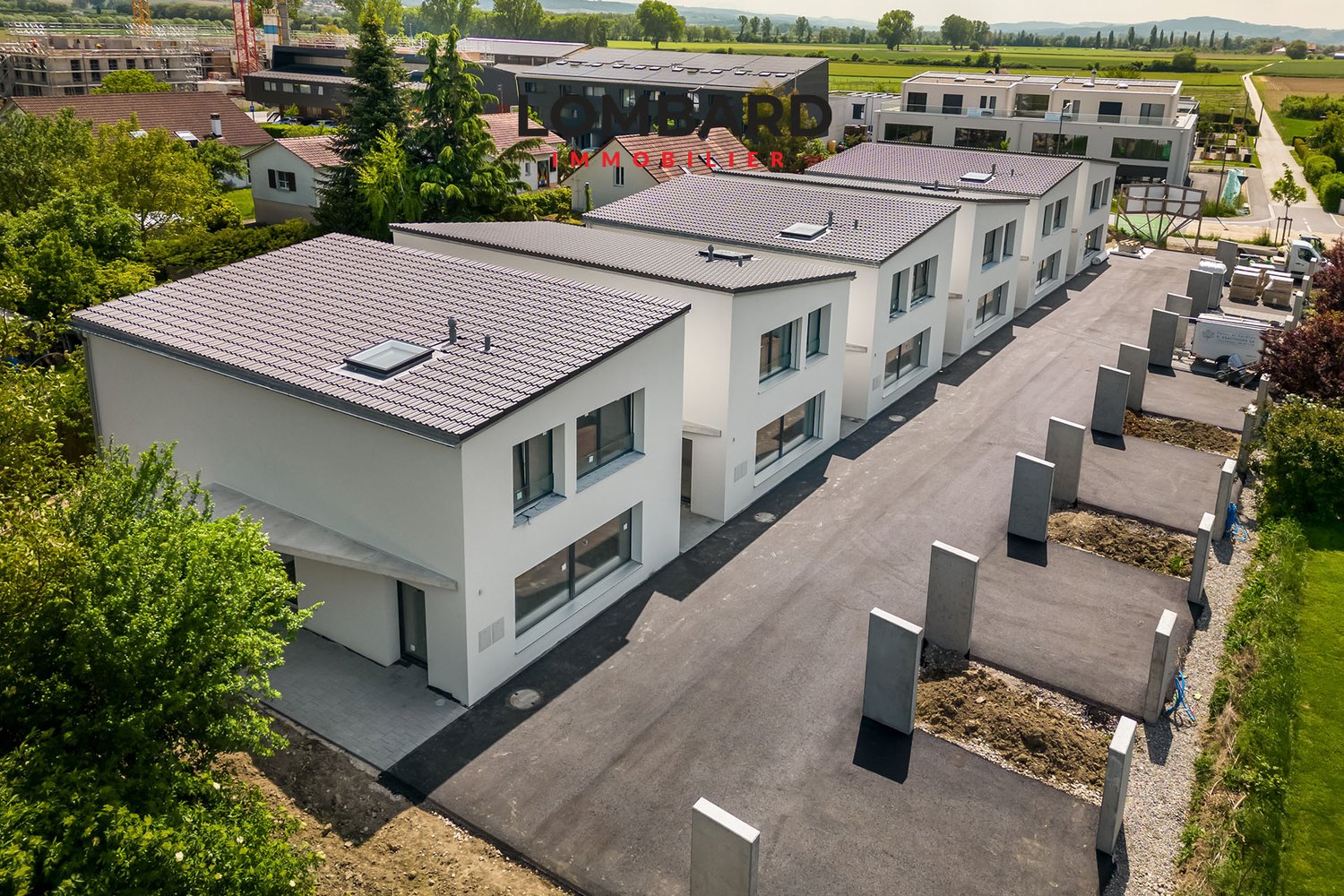 multiple buildings, grey roofs, multiple windows, several parking places in front