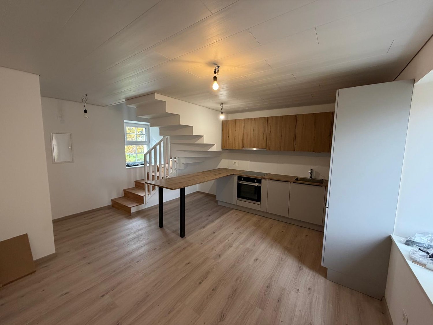 kitchen and dining area, wooden floors, kitchen island, wooden staircase, cabinets, sink, oven