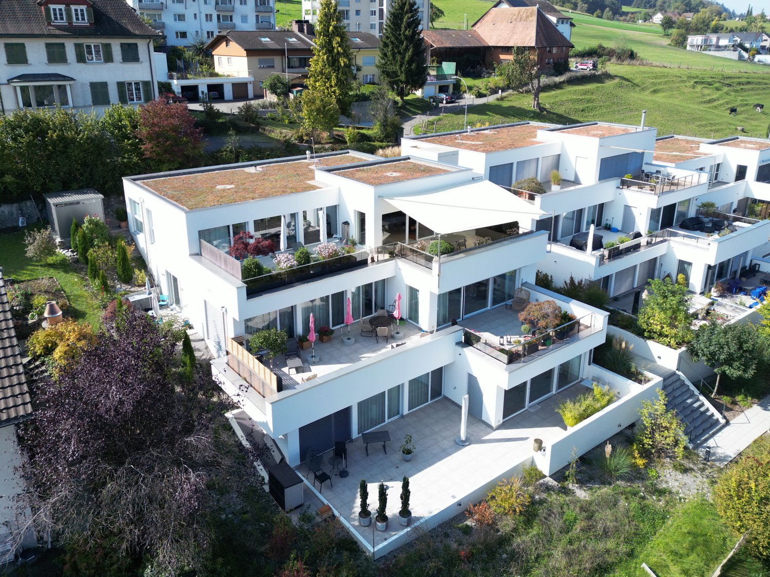 4-story apartment building, with multiple balconies, raised ground floor, lush gardens, green roofs, beautiful view