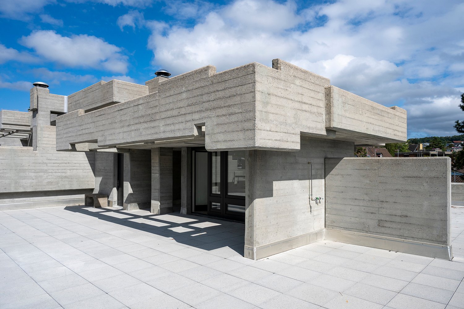 concrete structure, angular design, balcony, large entrance with glass doors