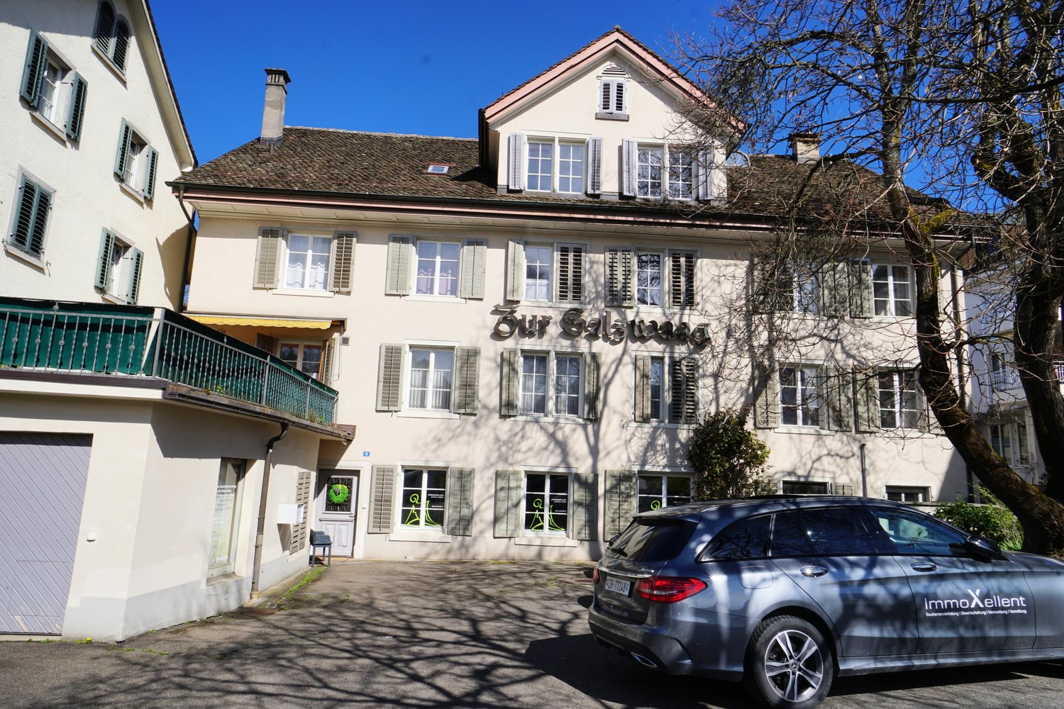 white building, brown roof, green shutter windows, terrace, garage, parked car