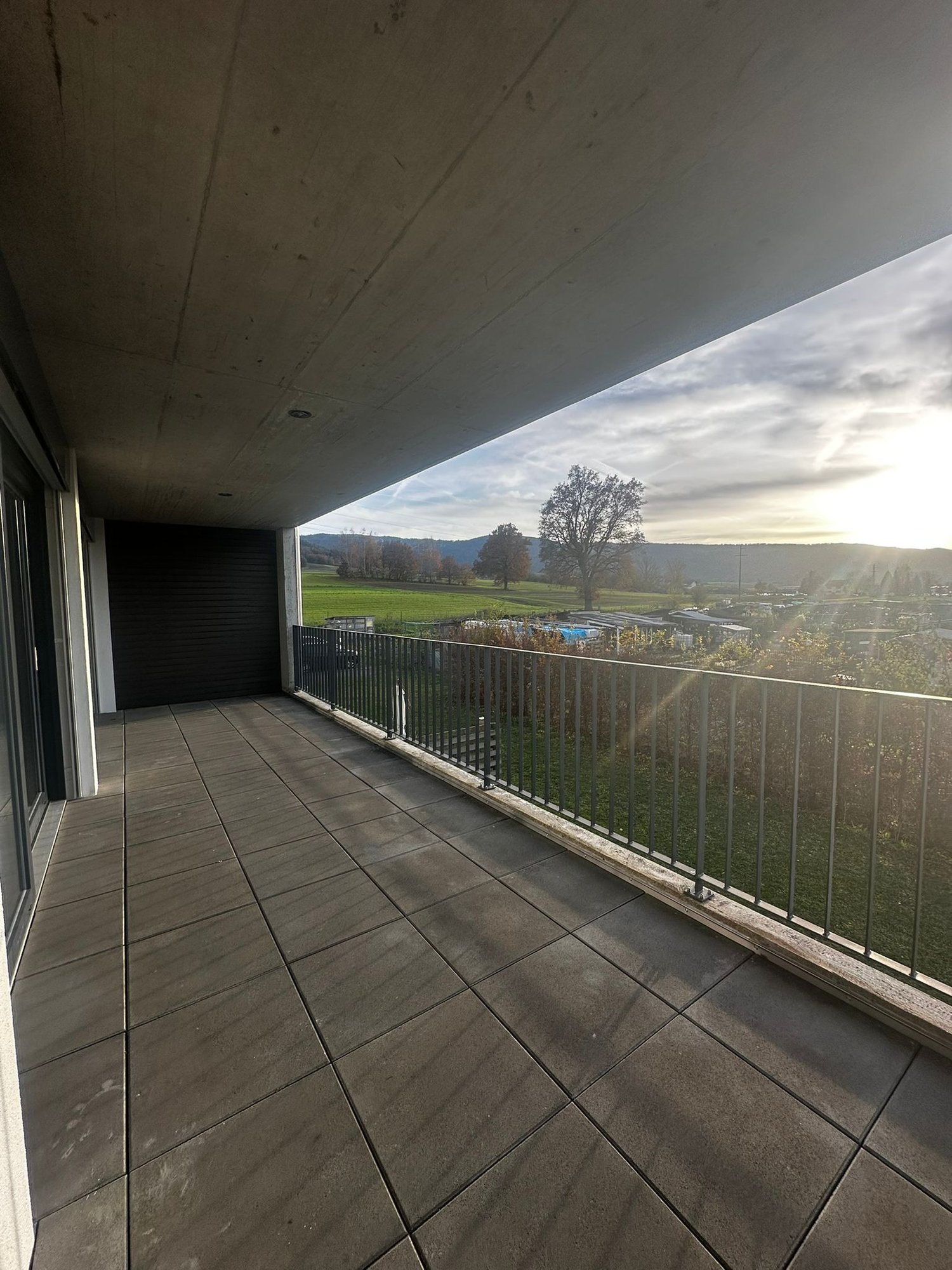 Tiled balcony, metal railing, outdoor view of grass and a pool