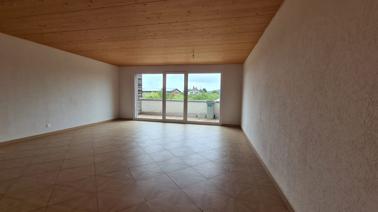 empty room with balcony, large windows, sliding glass doors, tiled floor, wooden ceiling