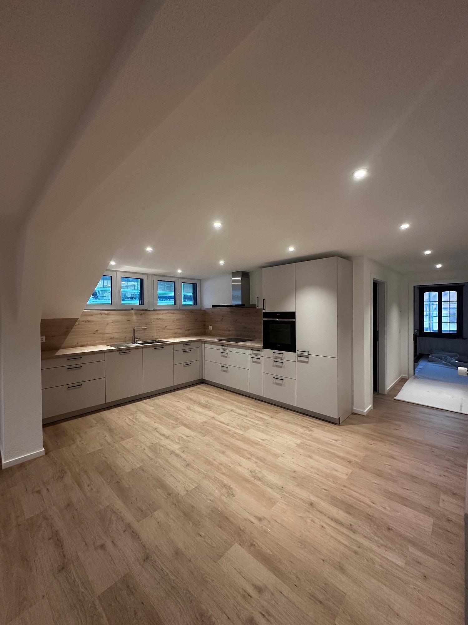 White cabinets, wooden floors, gas stove, oven, sink, and windows