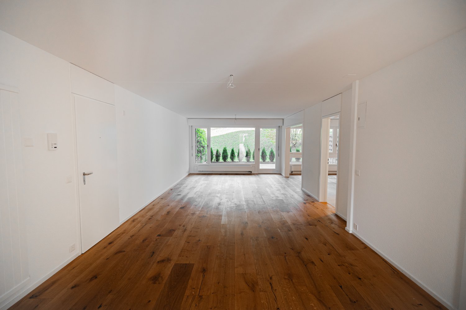 large room, wooden floor, white walls, 3 windows