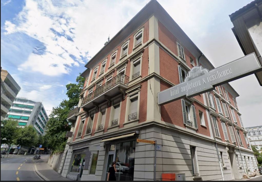 Three story building, brick walls, multiple balconies, modern storefront on ground floor