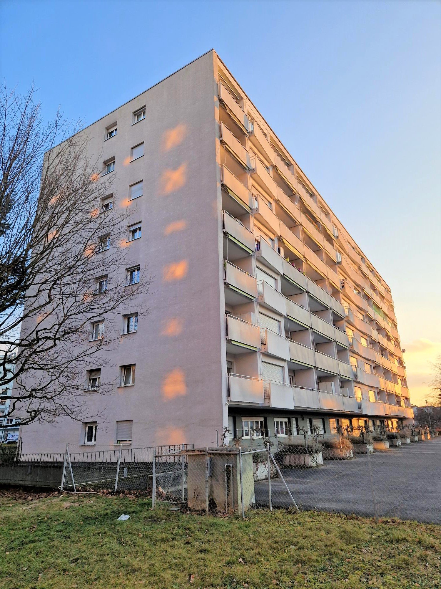Multi-story residential building, rectangular shape, balconies on each floor, concrete construction