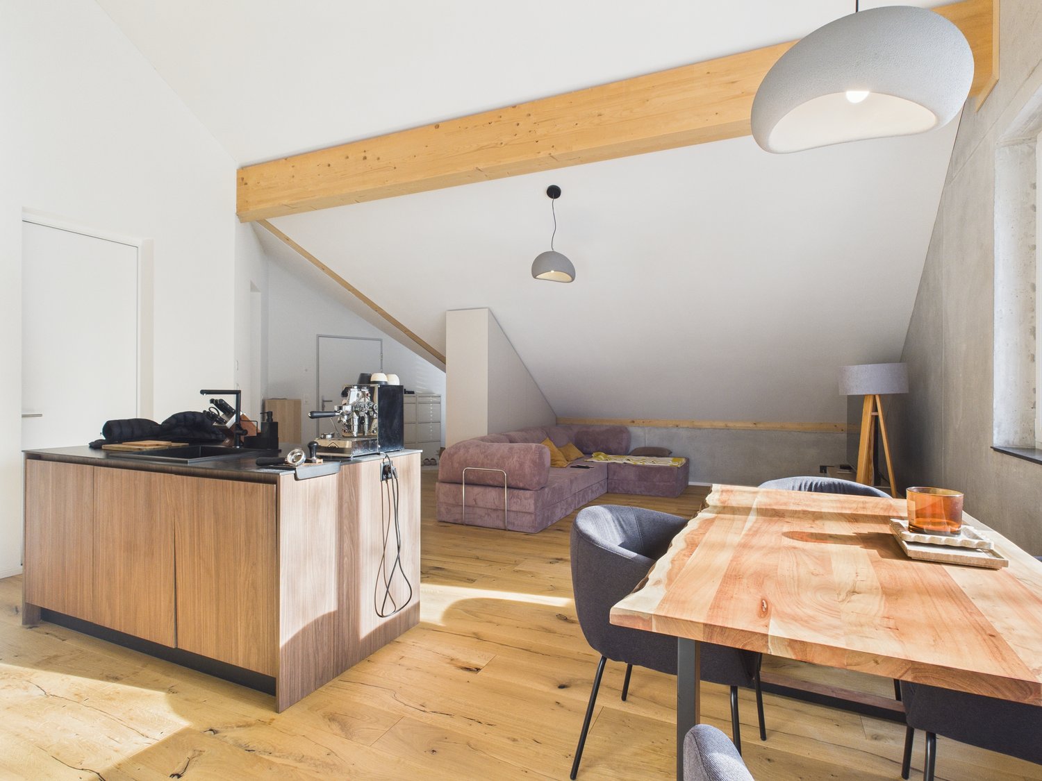 kitchen island, open concept layout, modern wooden furniture, pink sofa, dining table, wooden floor