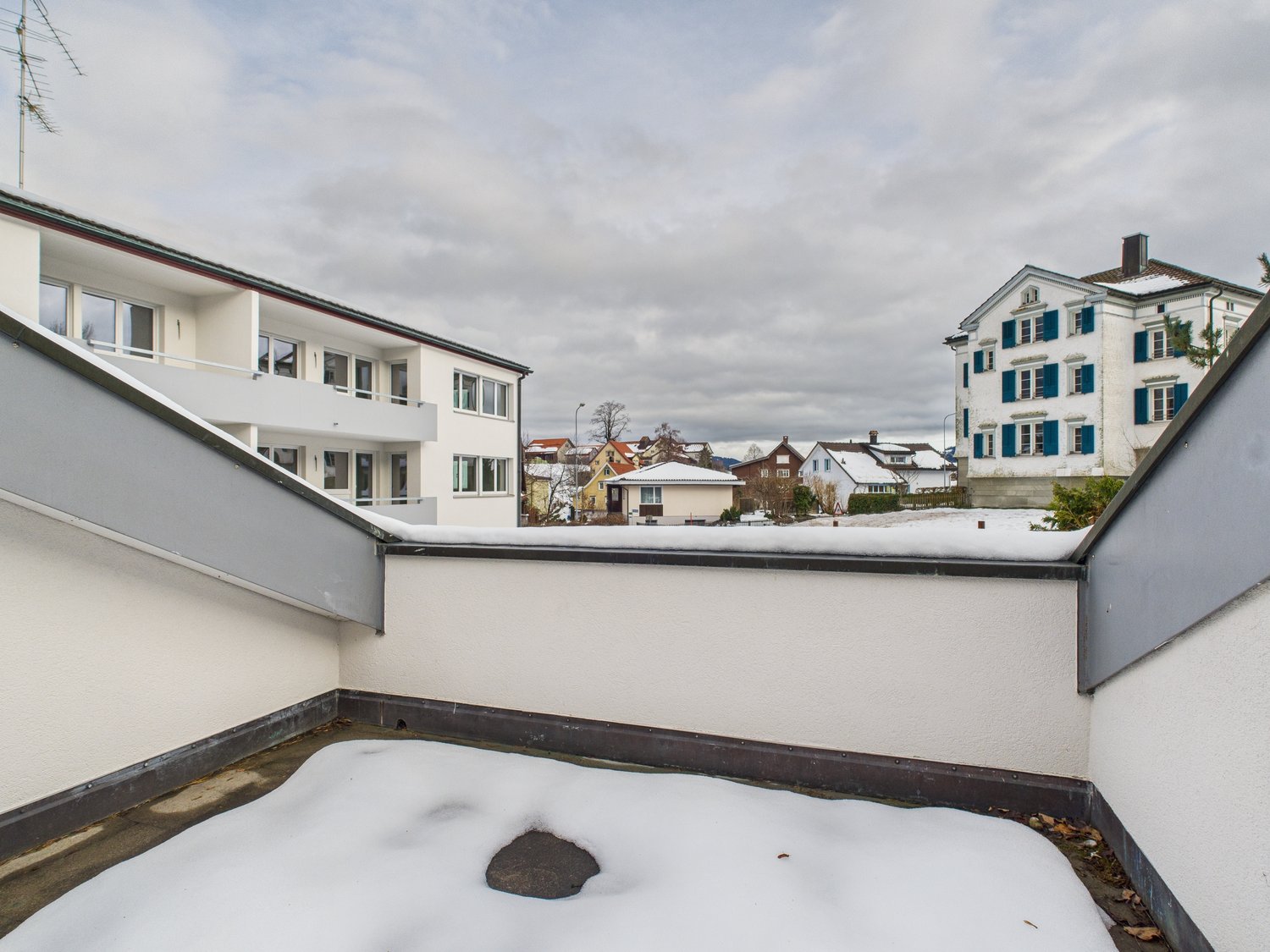 white concrete building, covered balcony, covered in snow
