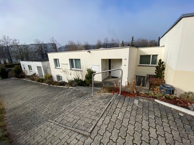 modern apartment building, white exterior, brick driveway, fenced garden, handrail on steps