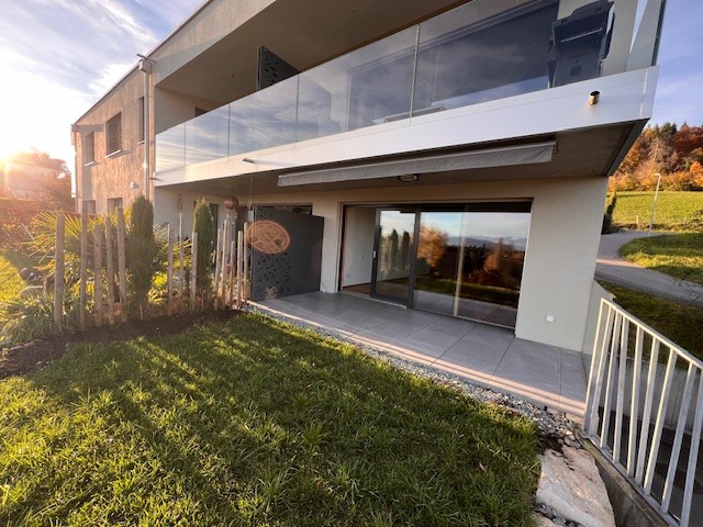 modern apartment with balcony, large windows, green lawn, sliding glass doors