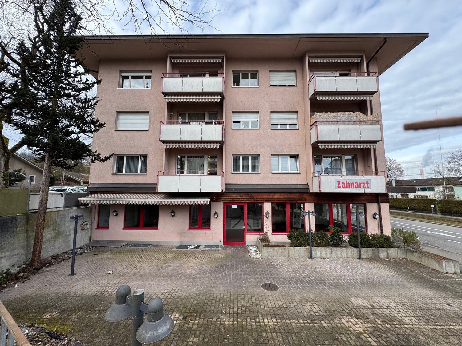 apartment building, balconies on each floor, awning above entrance, Zahnarzt text below top balcony