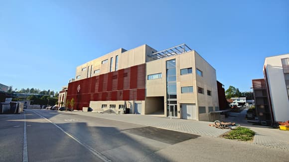 modern building, red panels, many windows, glass door, paved road