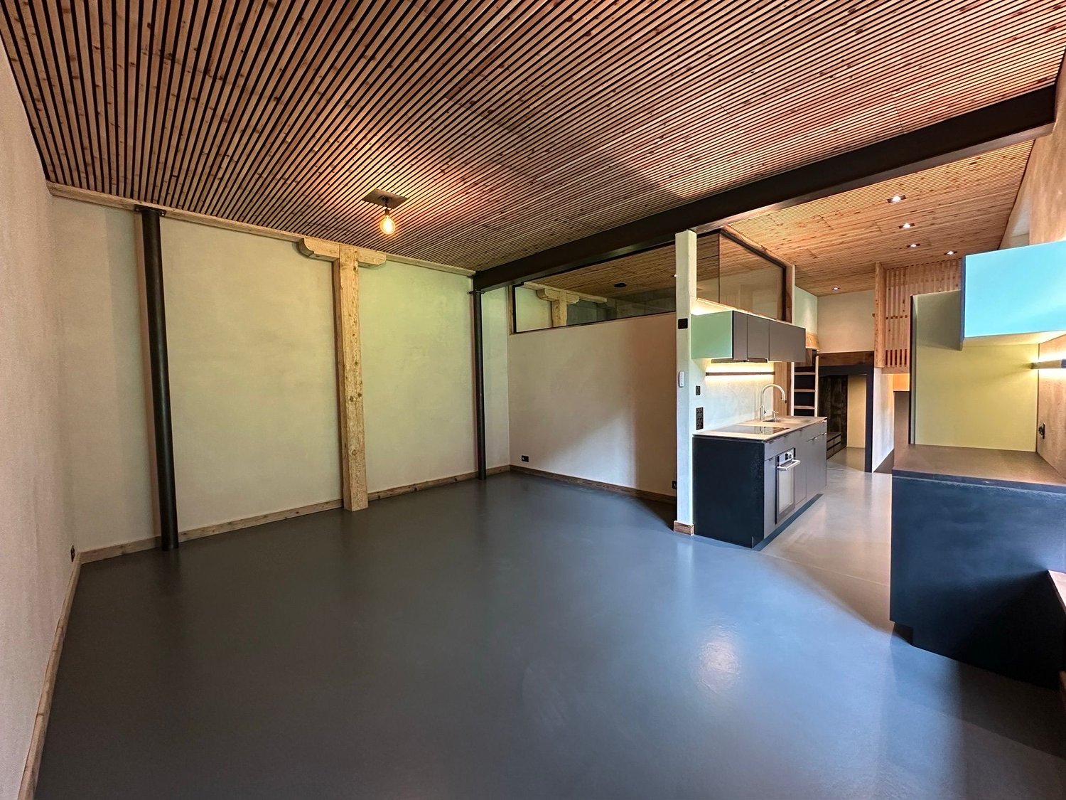 Empty kitchen with gray floor, white walls, wooden ceiling, sink, cabinets