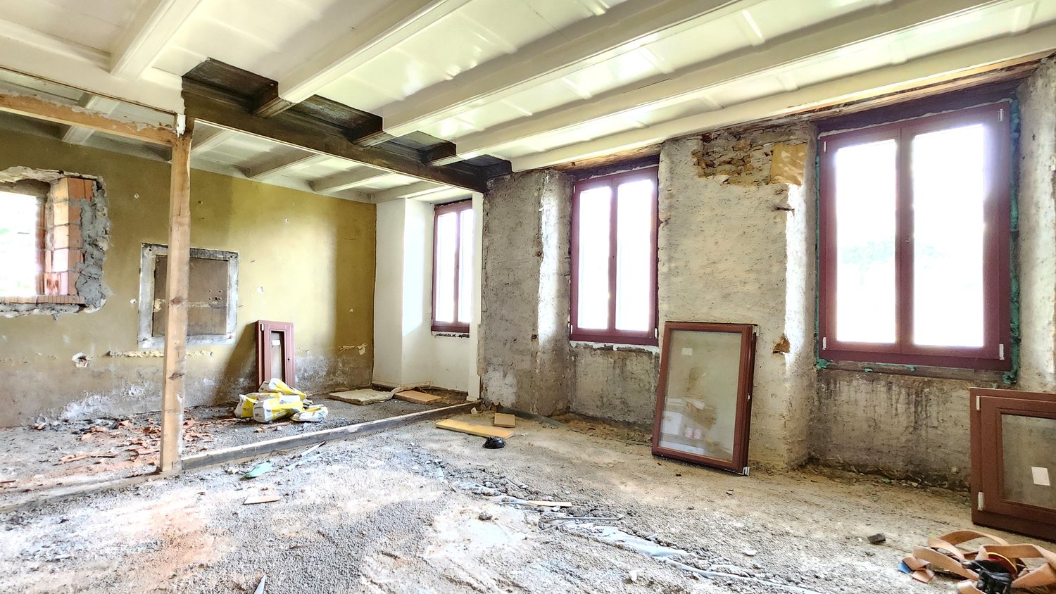 Partially demolished room with exposed walls, wooden beams, and debris on the floor. The room appears to be undergoing renovation or reconstruction work.