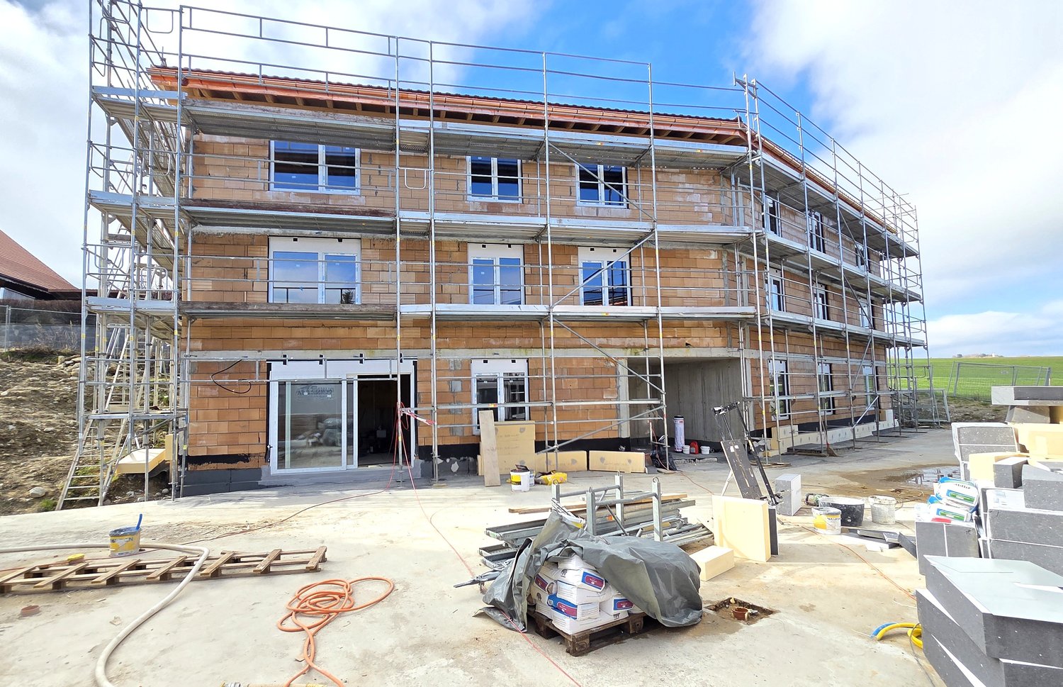 under construction, brick wall, glass windows, metal scaffolding, open doors, construction materials