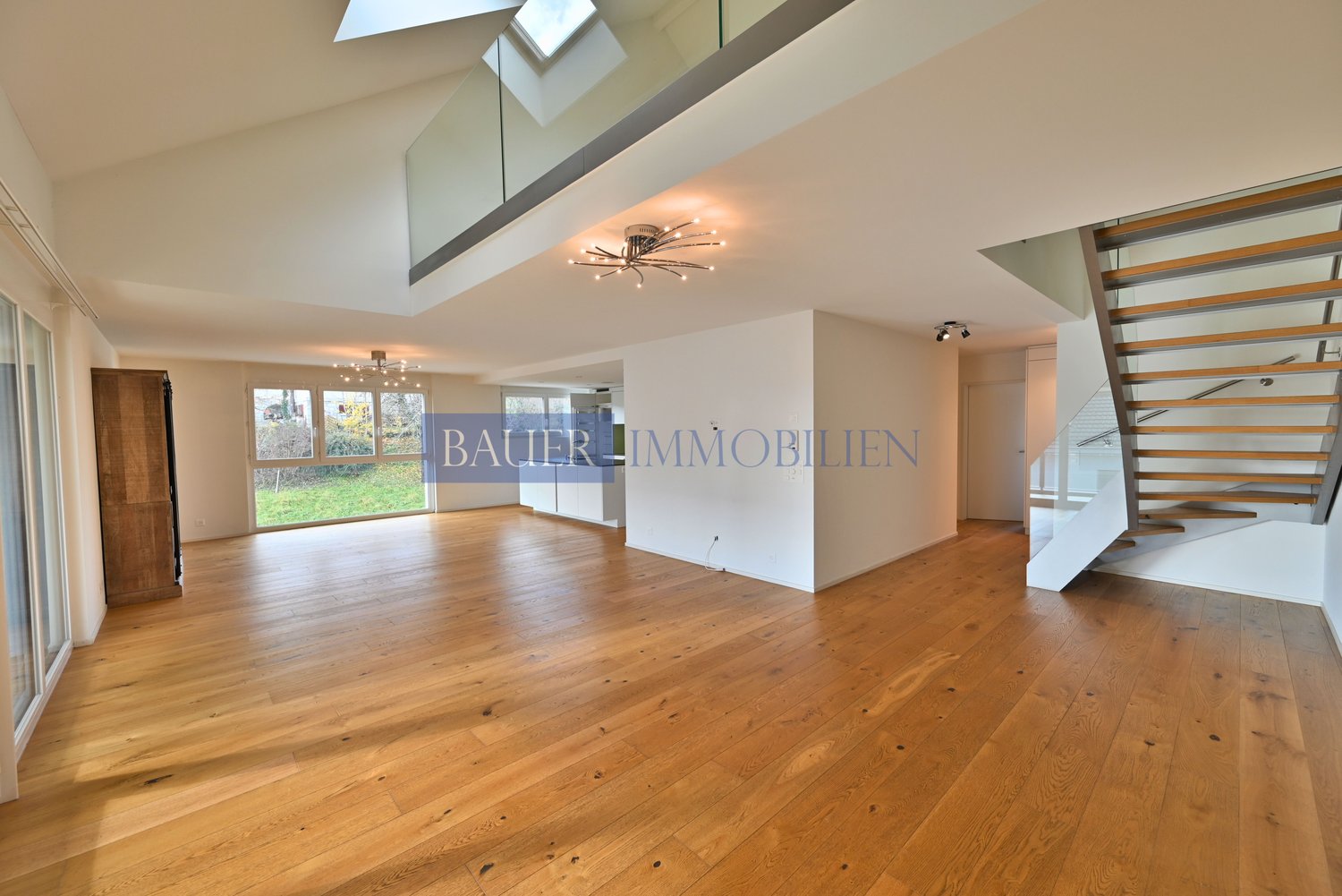 spacious open living area, large windows, wooden floors, two skylights, staircase