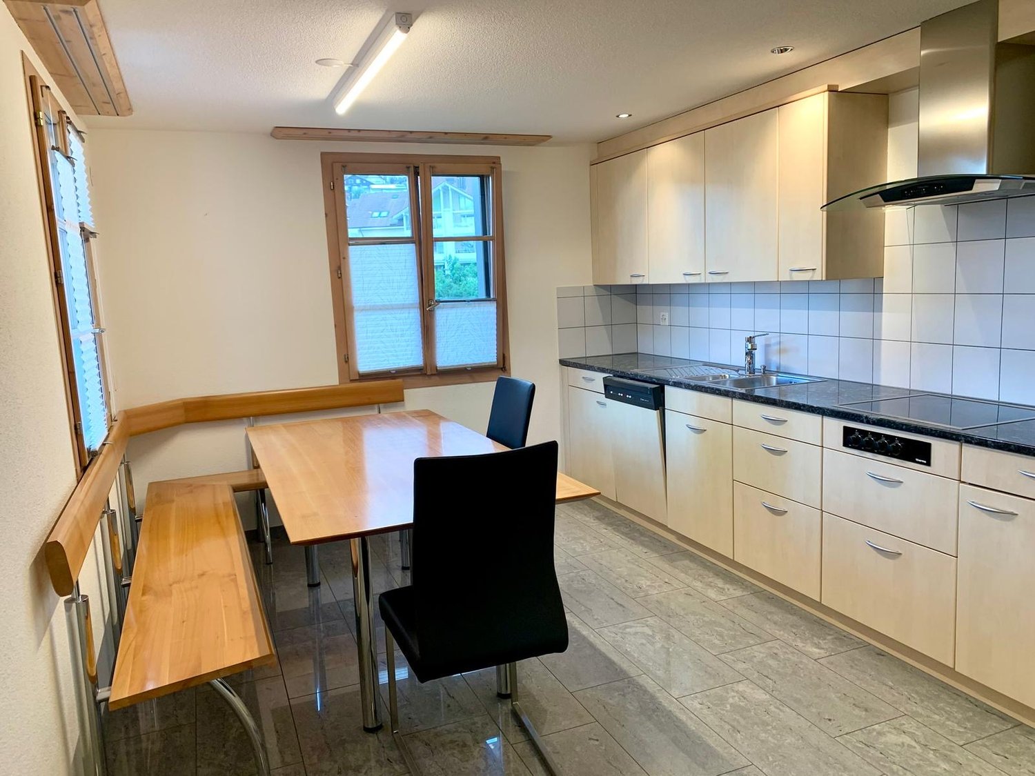 modern kitchen with dining area, wooden floor, window, wooden benches, wooden table, modern chairs, sink, kitchen cabinets, tiles