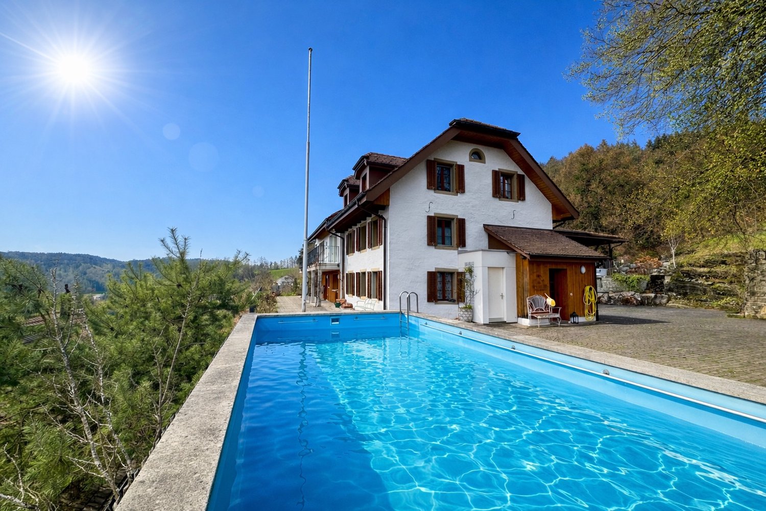 Detached house, white exterior, brown roof, large swimming pool, trees, mountains in the background