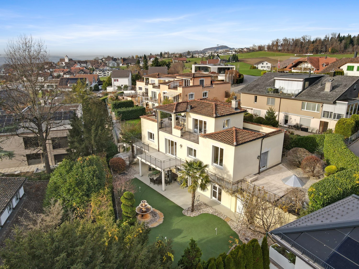 Modern townhouse with terracotta roof, large balcony, landscaped garden, green lawn area