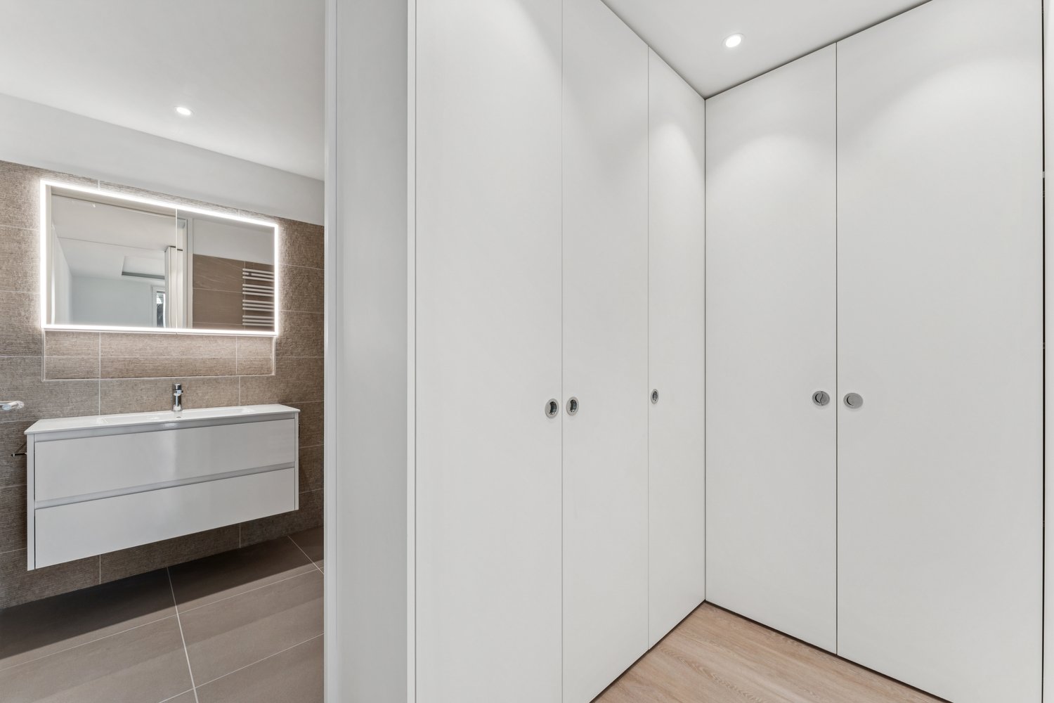 modern, white tiles, wooden floor, large mirror with lighting, double sink, four closets