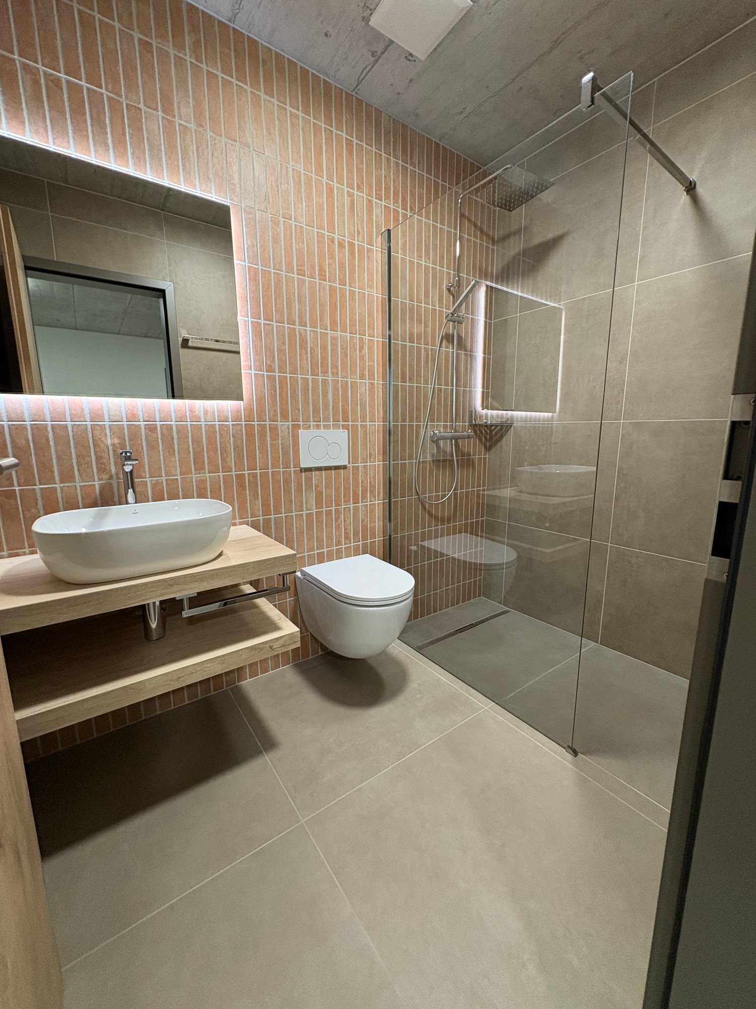 Bathroom with tile walls, shower, toilet, sink with faucet, and mirror.