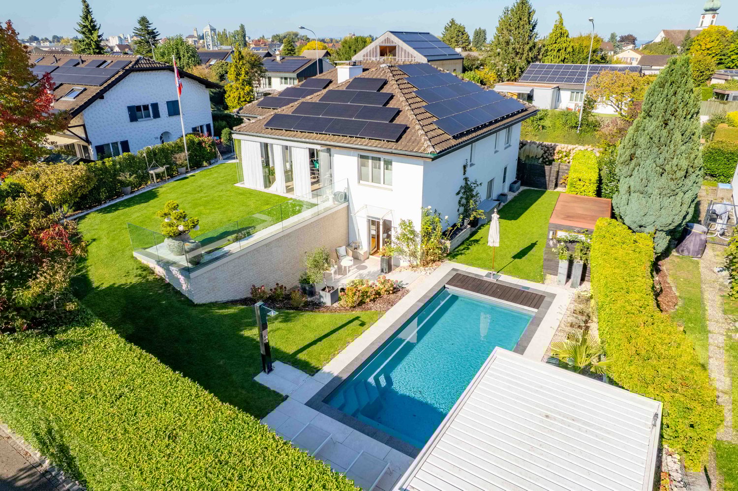 detached house, brown roof, solar panels, glass balcony, swimming pool, manicured lawn