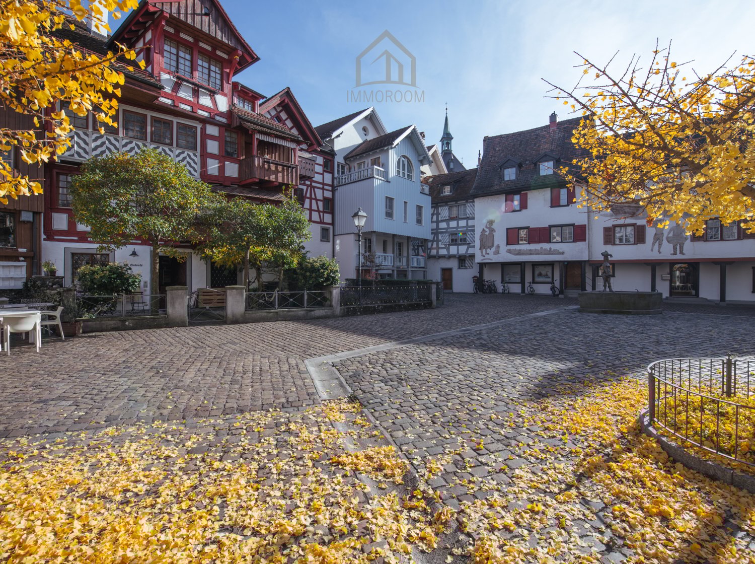 Historical buildings, paved courtyard, multiple balconies, trees, benches, lampposts