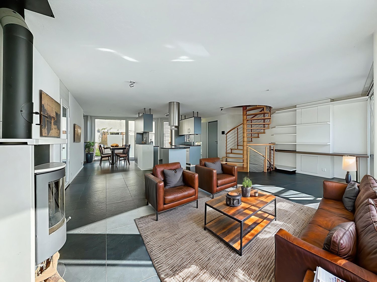 Open floor plan, fireplace, chandelier, spiral staircase, kitchen, dining area, living room, wooden floor, white walls